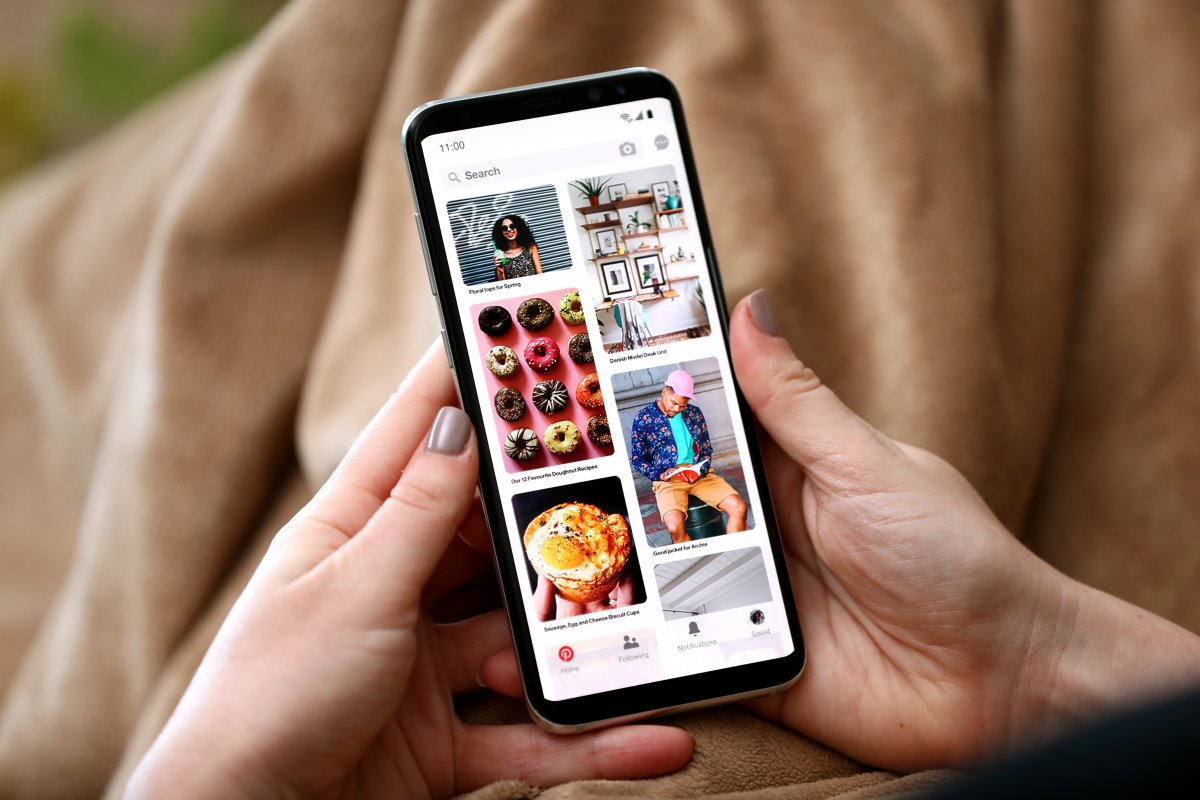 Hands holding a phone that show Pinterest on the screen