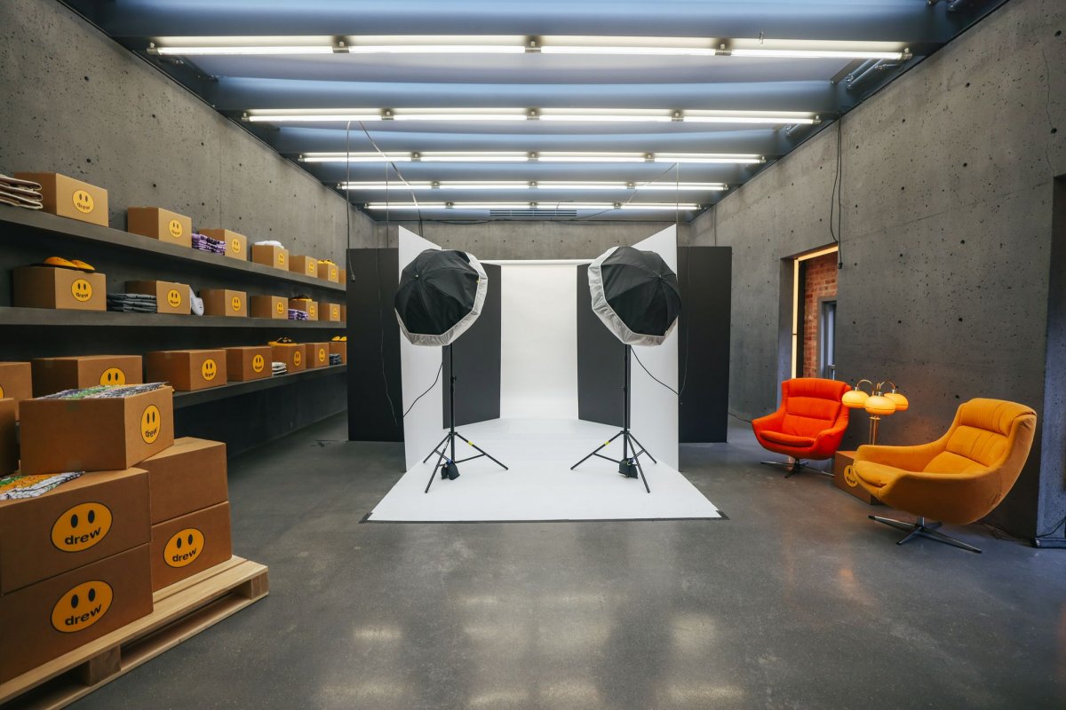 Industrial showroom with overhead lighting filled with cardboard boxes with smiley faces surrounded by lounge chairs and a photo set